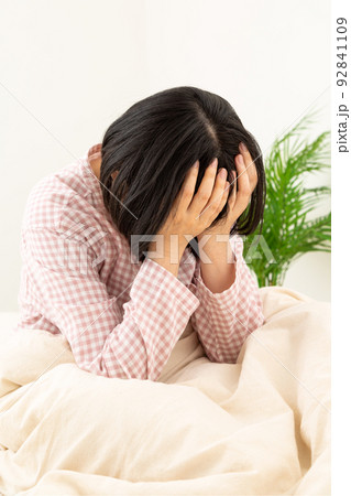 パジャマを着て寝室で悩むミドル女性 92841109