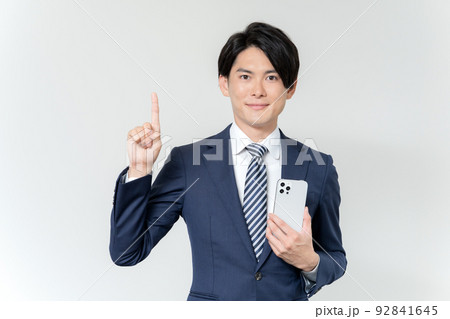 白背景のスマホを持って1番のポーズをする若いビジネスマンのポートレート 92841645