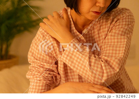 パジャマを着て寝室で肩こりに苦しむミドル女性 92842249