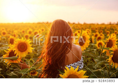 Girl with long hair stands with her back in field 92843893