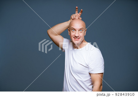 Funny bald male posing on a blue background with emotional 92843910
