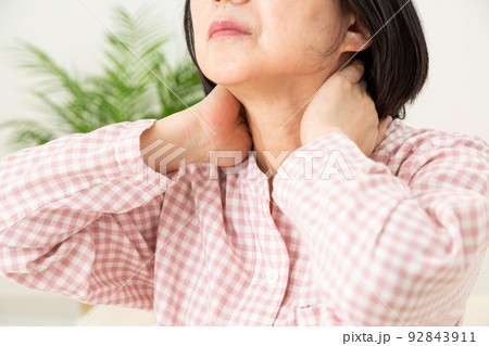 パジャマを着て寝室で肩こりに苦しむミドル女性 92843911