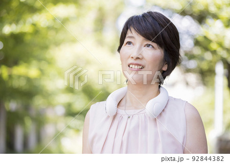 屋外でネッククーラーを使うミドル女性　ネックファン 92844382