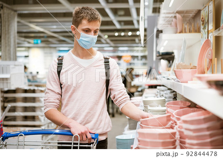 young man chooses dishes in the store young man chooses dishes in the store 92844478