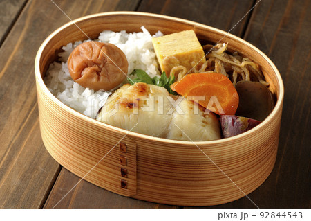 大きめの梅干しがご飯の上に乗っていて玉子焼や煮物なども入っている銀だらの西京焼き弁当 92844543