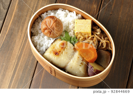 大きめの梅干しがご飯の上に乗っていて玉子焼や煮物なども入っている銀だらの西京焼き弁当を俯瞰で撮影 大きめの梅干しがご飯の上に乗っていて玉子焼や煮物なども入っている銀だらの西京焼き弁当を俯瞰で撮影 92844669