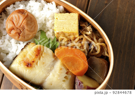 大きめの梅干しがご飯の上に乗っていて玉子焼や煮物なども入っている銀だらの西京焼き弁当を俯瞰で撮影 大きめの梅干しがご飯の上に乗っていて玉子焼や煮物なども入っている銀だらの西京焼き弁当を俯瞰で撮影 92844678
