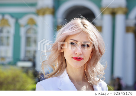 Beautiful young woman, with blond curly hair and smiling in the street. Outdoor 92845176