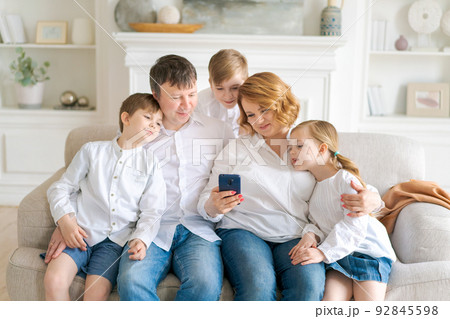 Happy cheerful caucasian family dad mom and kids having fun and using digital Happy cheerful caucasian family dad mom and kids having fun and using digital 92845598