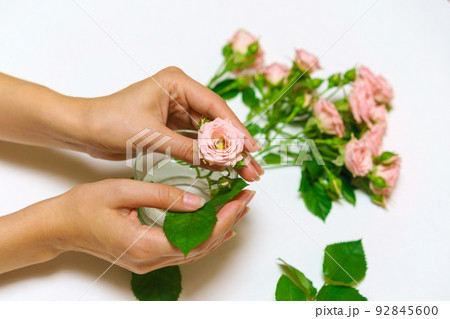 Close-up of woman florist's hand making bouquet of pink roses on a light table. Close-up of woman florist's hand making bouquet of pink roses on a light table. 92845600