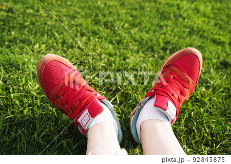 female legs in sneakers on a background of green grass female legs in sneakers on a background of green grass 92845875