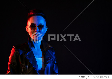 Portrait of stylish woman with short hair in leather jacket and round glasses Portrait of stylish woman with short hair in leather jacket and round glasses 92846291