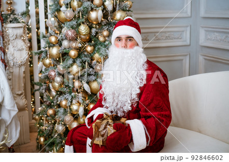 Santa Claus holding a gift in mittens on a Christmas tree 92846602