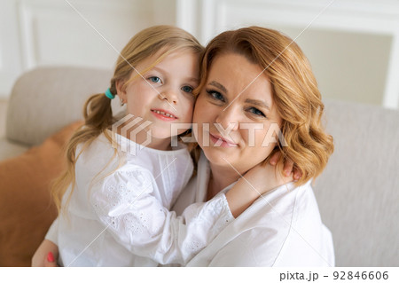 Close-up cropped image smiling little daughter hugging caucasian mom, family Close-up cropped image smiling little daughter hugging caucasian mom, family 92846606