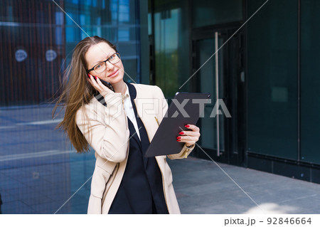 Business woman with glasses talking on the phone near the business center 92846664