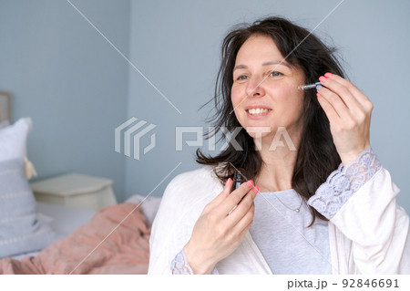 Woman touching clean side eye contour with an anti-bagging pipette, serum 92846691