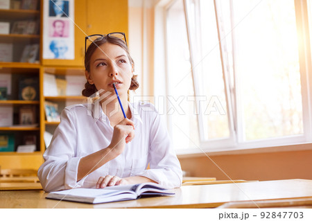 Young woman studying for test exam. Tutor writes books in notebook. Caucasian 92847703