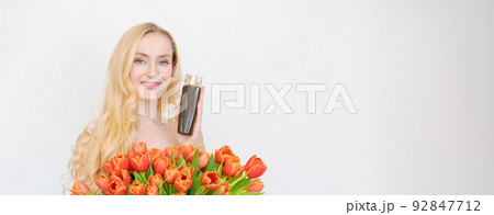 Studio portrait gorgeous blonde woman with long wavy hair holding bouquet red 92847712