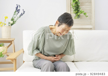 自宅で腹痛を感じるシニア女性 92849483