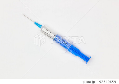 Blue medical disposable syringe for injection on a white background. Medical instrument for vaccination. 10 ml syringe for COVID-19 vaccine. Medical equipment. Isolated. Top view. Close-up  92849659
