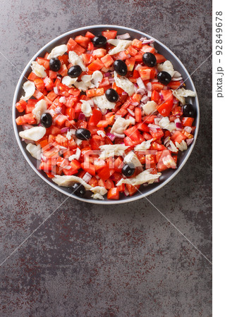 Catalan codfish salad as known as esqueixada, with cod, tomato onion and olive close-up in a plate. Vertical top view 92849678
