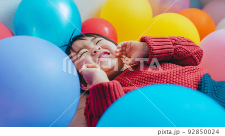 風船に囲まれて嬉しそうな子ども 92850024