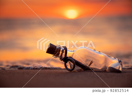 Message in the bottle against the Sun setting down 92852514