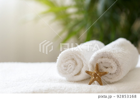 Rolled white towels on the bed in the hotel room 92853168