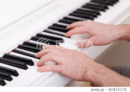 Young man playing on white modern piano Young man playing on white modern piano 92853170