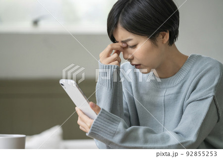 スマホを持って頭を抱える若い女性 92855253