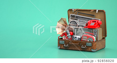 Vintage electrical and electronic appliances in an old suitcase. Nostalgic retro objects from the past 1960s - 1980s on green backgound. 92856020