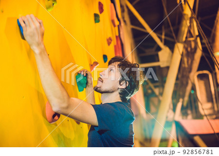 Man climber on artificial climbing wall in bouldering gym 92856781