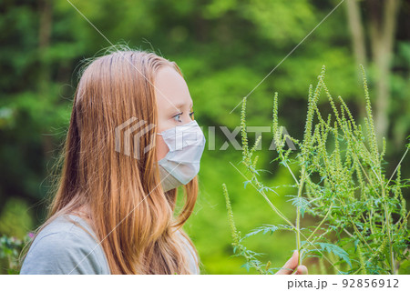 Young woman in a medical mask because of an allergy to ragweed Young woman in a medical mask because of an allergy to ragweed 92856912