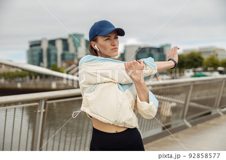 Beautiful sportive woman doing stretching exercise on footbridge in the city  92858577