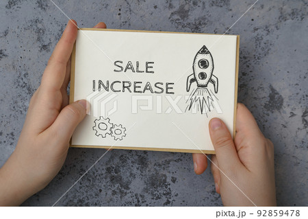 Woman holds card with words Sale Increase on concrete 92859478