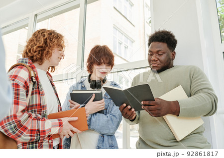 African American guy and two teenage girls looking through lecture notes 92861817
