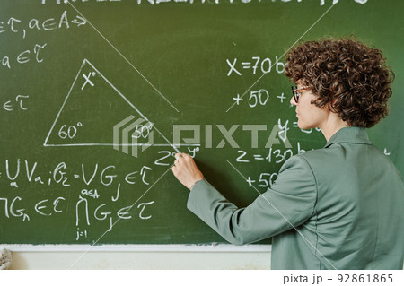 Young serious teacher of college or university drwing triangle on blackboard Young serious teacher of college or university drwing triangle on blackboard 92861865
