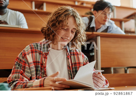 Smiling teenage student of highschool or college looking through notes 92861867