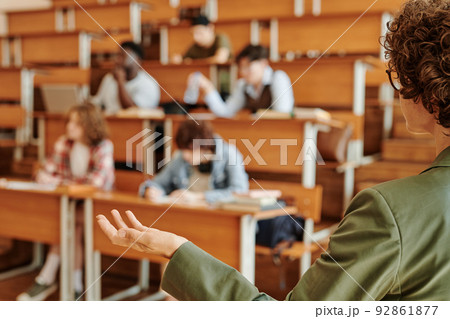 Young confident college teacher or lecturer explaining one of lesson points Young confident college teacher or lecturer explaining one of lesson points 92861877