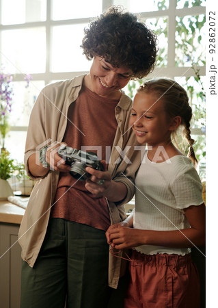 Young smiling woman in casualwear showing new photos to her daughter 92862072