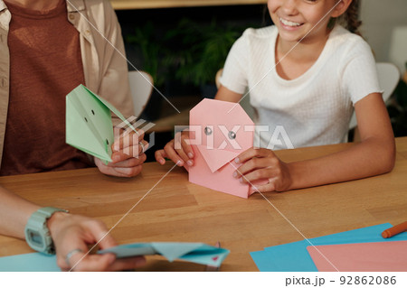 Hands of young woman and happy youthful girl with handmade origami Hands of young woman and happy youthful girl with handmade origami 92862086