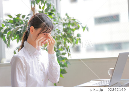 目の疲れでこめかみを指でおさえる女性1 92862149