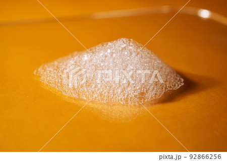 White foam from shampoo or shower gel on a bright yellow background. 92866256