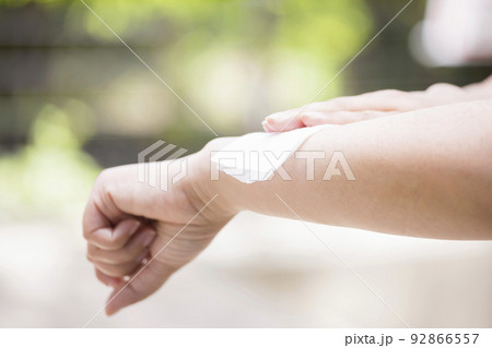 虫よけシート　汗吹きシートを使うミドル女性手元 92866557