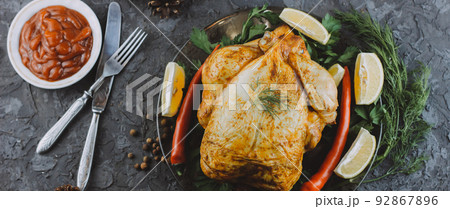 Roasted turkey or chicken. The Christmas table is served with a turkey decorated with bright tinsel. Fried chicken. table setting. Christmas dinner. Photo banner. top view on wooden background 92867896