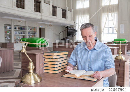 Portrait of caucasian Senior man working with book in public library. Adult student at the library 92867904