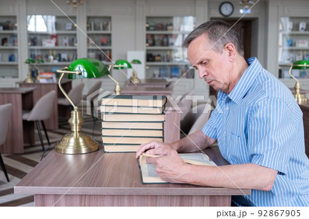 Portrait of caucasian Senior man working with book in public library. 92867905