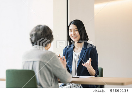 シニア女性に説明をする女性 92869153