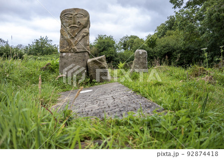 This is a bronze age stone carviing with two faces,called Janus, located In Caldragh Cemetery on Boa Island, Lower Lough Erne. Northern Ireland 92874418