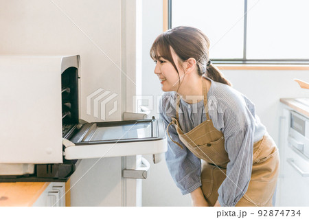 電子レンジ・オーブンを使う女性（笑顔） 92874734